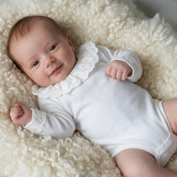 Bebê usando body branco com gola de renda