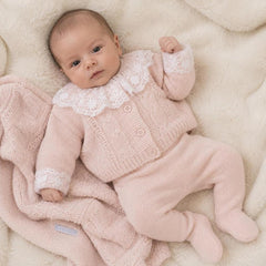Bebê usando body branco com gola de renda por baizo de casaco de tricot rosa